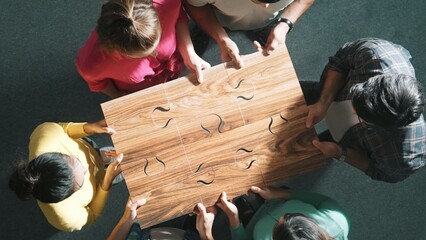 Top down view of business people gathering jigsaw together at meeting. Aerial view of diverse team...
