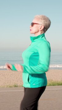 71 year old woman gets her exercise at the beach in Southern California. Vertical Video.