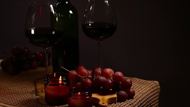 Still life two wine glasses with grapes bunch near romantic aroma burning flame fire candles on a table on dark backround. Decor concept of Christmas holiday celebration with fresh sweet ripe dessert