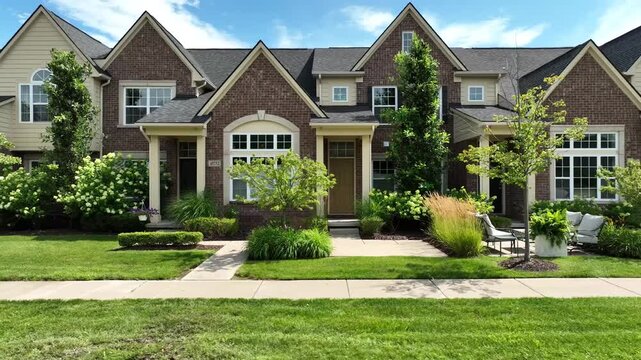 4K side-scroll view of elegant brick townhomes with gabled roofs, lush landscaping and blue sky&mdash;quiet, walkable condo community ideal for real estate and lifestyle storytelling.