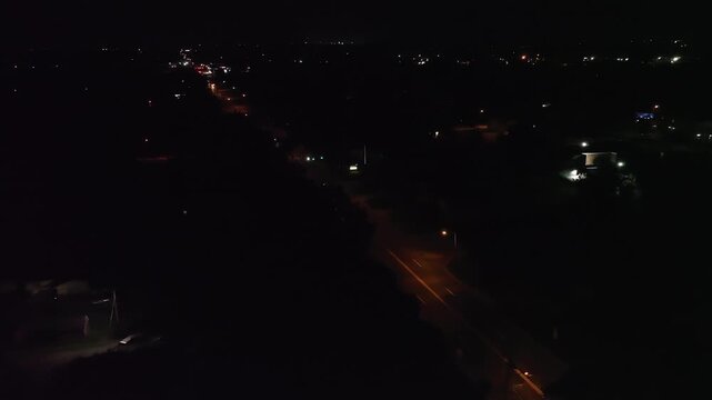 Aerial 4K drone night view of a suburban street with glowing streetlights and sparse traffic&mdash;moody, ominous, cinematic b-roll perfect for documentaries, news, and media.