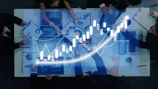 A professional team engages in a business meeting, analyzing financial metrics and strategies with charts overlaying their discussion to signify growth and insight. Axiom