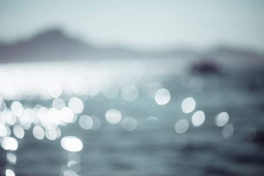Shimmering sea surface captured out of focus with sparkling bokeh reflections and a distant horizon, evoking dreamy coastal light and abstract seaside texture - Powered by Adobe