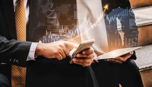 Two business professionals engage in a discussion on financial growth, utilizing technology like a smartphone and tablet, with an overlay of market analytics. Scalp