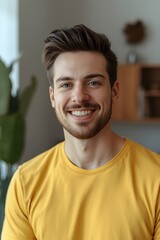 Warm natural portrait of a young man smiling confidently indoors, surrounded by soft daylight and subtle home d&eacute;cor details, highlighting an approachable expression and relaxed atmosphere suitable for