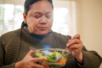 Body positivity plus size woman self love enjoying fresh salad at home with natural light and calm mood, mindful eating scene shows gentle focus and warm atmosphere