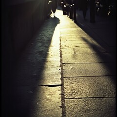 Sunlit city sidewalk, long shadows stretching