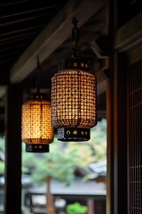 Two traditional Japanese lanterns hang in a covered walkway. Soft light illuminates intricate woven patterns