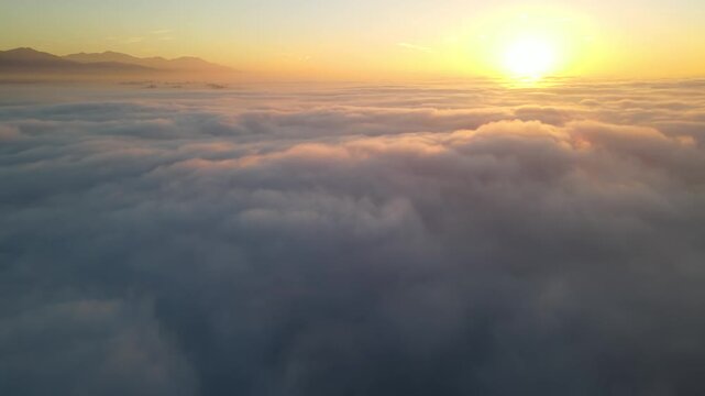 Aerial shot of the sunrise above a layer of clouds
