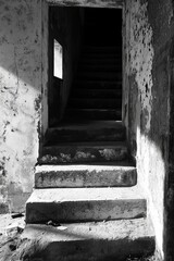 Obraz premium Sunlit steps, crumbling interior, dark passage