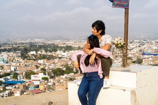 Young couple contemplating city view from hilltop