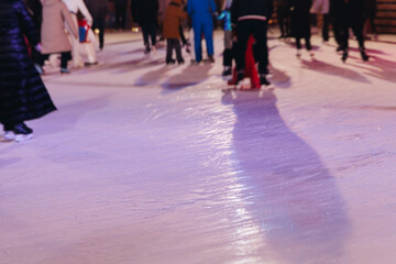 Ice skating on the ice rink arena with people, skating rink surface, ice skating in winter city, winter activities, holiday christmas time, with new year decoration and illumination, ice skates boots
