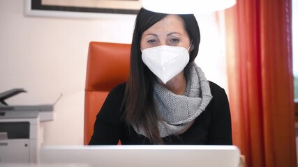 Woman wearing mask in covid pandemic working with her laptop