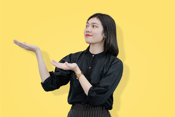 Fototapeta premium young business woman showing to the side for copy space. suitable for branding product yellow studio background