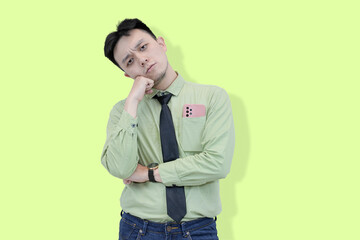 A focused young Asian professional posing with contemplative expression, symbolizing problem-solving or searching for an idea against a light green background