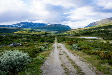Remote gravel road leading through vast mountain tundra © Janica