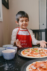 Young boy happily helping prepare a homemade pizza 