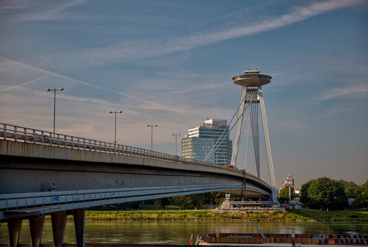 Bratislava, Slovakia &ndash; July 24, 2025: The UFO Observation Tower atop the SNP Bridge spans the Danube River under a bright morning sky.
