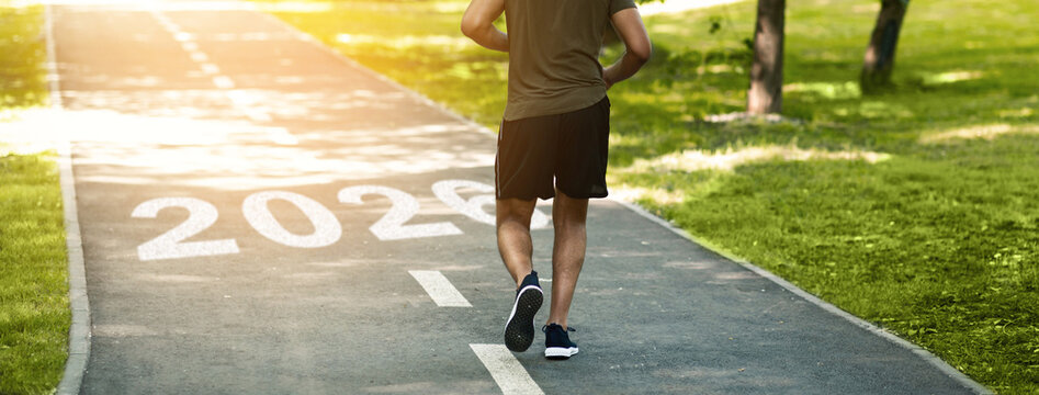 A man strolls down a scenic path in a green park, surrounded by trees and sunlight. The path features the year 2026, suggesting a future focus. He appears relaxed and engaged with nature.