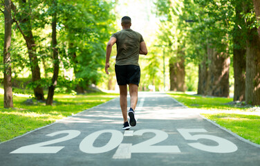 A man jogs along a tree-lined path in a vibrant park, with the year 2025 painted on the ground. The scene captures a sense of progress and health in an outdoor setting.