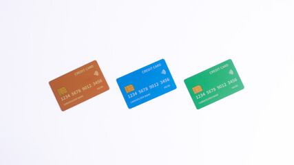 Three credit cards in gold, blue, and green arranged diagonally on a white background, symbolizing finance, digital payment, banking security, or diverse credit options and consumer choices.
