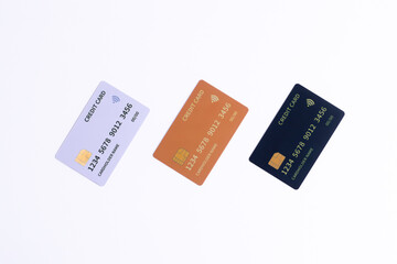 Three credit cards in white, gold, and black arranged diagonally on a white background, symbolizing finance, digital payment, banking security, or diverse credit options and financial choice.
