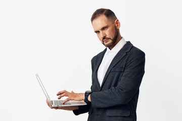 Business professional man on an isolated colored background, focused expression, typing on a laptop, conveying confidence, ambition, calm determination, and strategic intent.