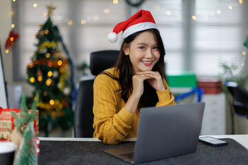 Happy asian young woman typing an email on laptop on Christmas at home.