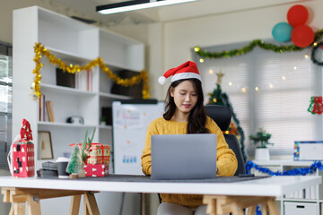 Happy asian young woman typing an email on laptop on Christmas at home.