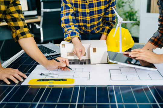 Engineers collaborate on architecture models with solar panels, showcasing teamwork, innovation, and sustainable construction for a green future