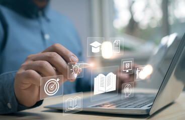 Businessman using laptop with digital education and e-learning icons representing online courses, knowledge management, innovation, and smart learning technology for modern education concept.