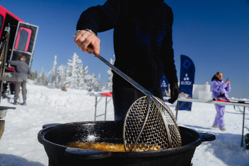 Large mesh oil skimmer in the foreground, outdoor cooking over a fire