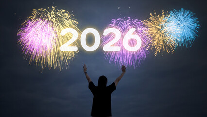 Person with arms raised celebrating the New Year 2026, watching colorful fireworks light up the night sky for the holiday countdown.