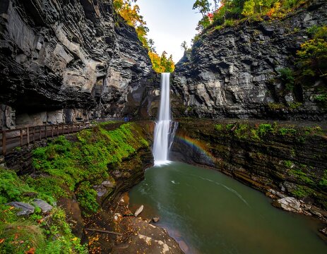 Cascading waterfall plunges into pool below, flanked by rocky cliffs in autumn sunlight