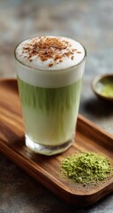 A matcha latte in a glass, topped with whipped cream and cocoa