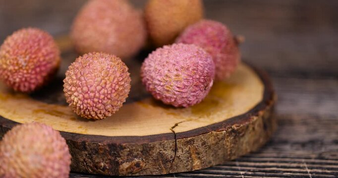 ripe red lychees on a wooden table, ripe red-skinned lychee fruits,rough textured lychee peel closeup