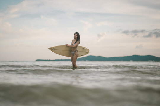 Sexy woman holding surfboard sport related to surfing vacations healthy living and active beach lifestyle.