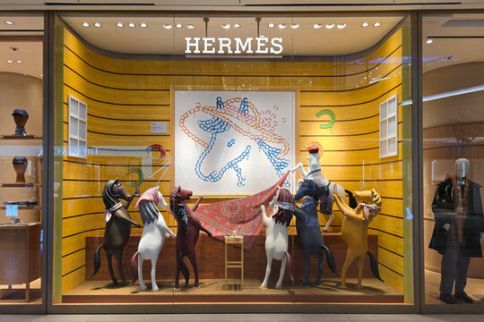 Kuala Lumpur, Malaysia &ndash; Sep 14, 2025: Exterior view of the Hermes boutique featuring an artistic window display with scarves, accessories, and horse-themed decorative figures.