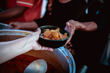 The hands of the hungry are asking for food from the donor