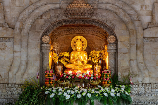 Interior scene of the Buddhist temple of dharma giri vihara in Northern Bali, Indonesia, showing golden sculpture depicting Buddha. 
