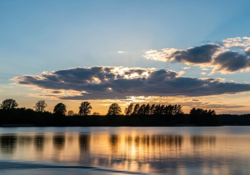 Serene sunset over calm water with silhouetted trees and dramatic clouds