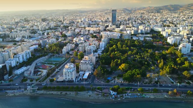Aerial panoramic view of Limassol, Cyprus, highlighting the modern skyline, residential areas, and green spaces. The image captures the vibrant city life, urban development.