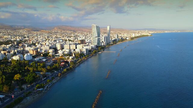 Aerial panoramic view of Limassol, Cyprus, highlighting the modern skyline, residential areas, and green spaces. The image captures the vibrant city life, urban development.