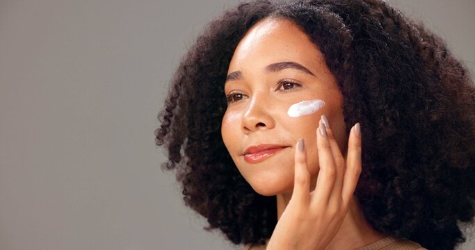 Skincare, cream and woman in studio, happy or healthy skin with cosmetics, thinking and mockup space. Anti aging, face and person with lotion for glow, gray background and self care with dermatology