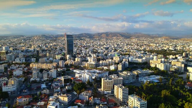 Aerial panoramic view of Limassol, Cyprus, highlighting the modern skyline, residential areas, and green spaces. The image captures the vibrant city life, urban development.
