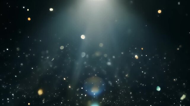 A mesmerizing display of shimmering silver and gold particles illuminated by a bright light from above on a dark background.