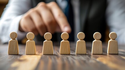 A hand pointing at a wooden figure on a wooden table.