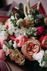 Soft natural light bouquet of pastel roses, carnations and white flowers with eucalyptus in elegant wrapping, close-up romantic still life without people