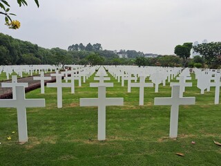 
Ereveld Ancol war cemetery in Jakarta, Indonesia, with neatly arranged white gravestones surrounded by green lawns and trees, creating a solemn and peaceful memorial atmosphere.