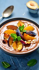 Chocolate dessert with plum wedges, mint sprigs, and chopped nuts in a dark bowl